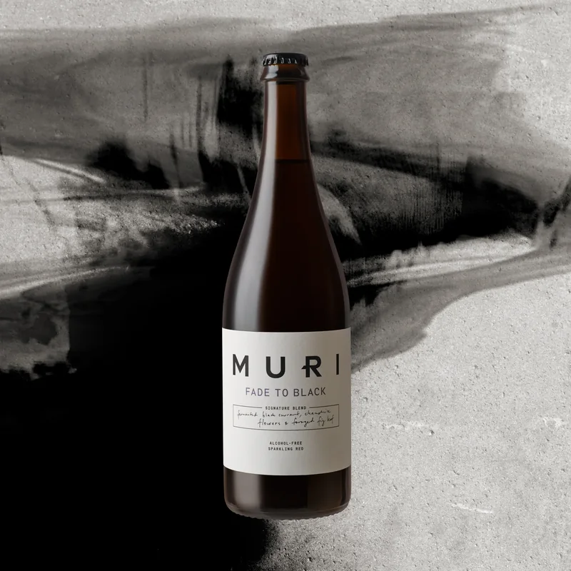 uma garrafa de MURI Fade to Black sobre pinceladas negras em betão